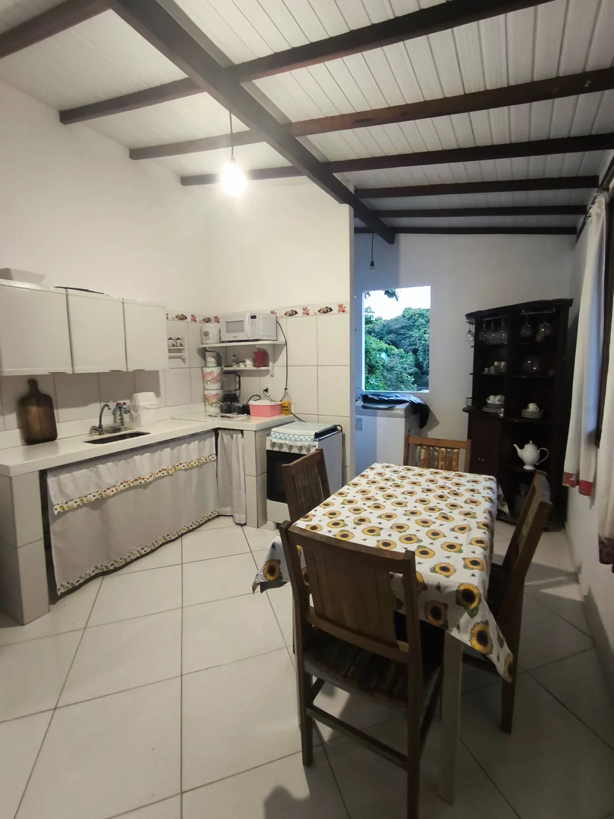 Cozinha integrada à sala de jantar da Casa da Lau em Trancoso, com telhado de vigas aparentes