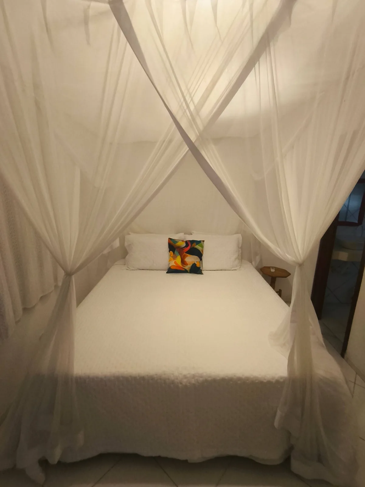 Suíte com cama queen e mosquiteiro branco na hospedagem em Trancoso BA