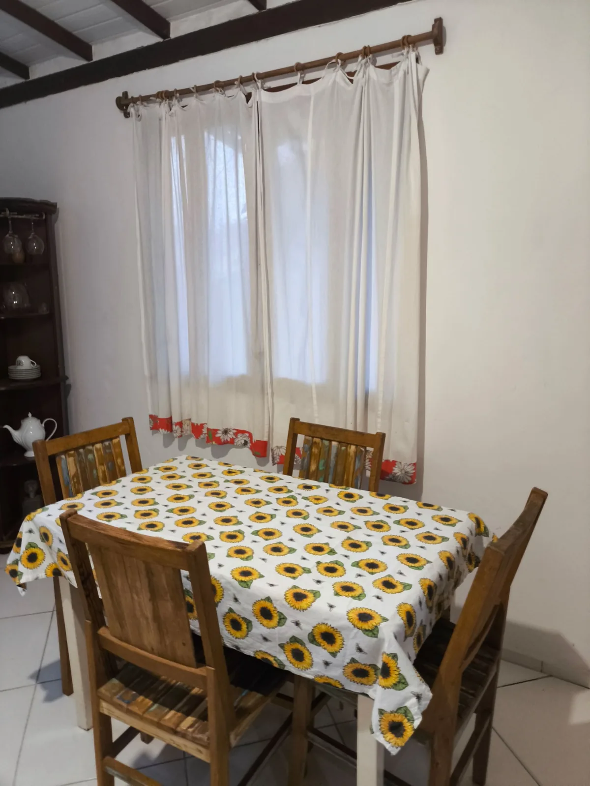 Sala de jantar da hospedagem em Trancoso BA com mesa de madeira para seis pessoas e cristaleira antiga